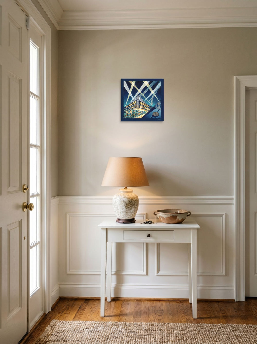 A 12x12 inch canvas Art Deco print of 'The New Age Spectacle' hanging in an entryway near a console.