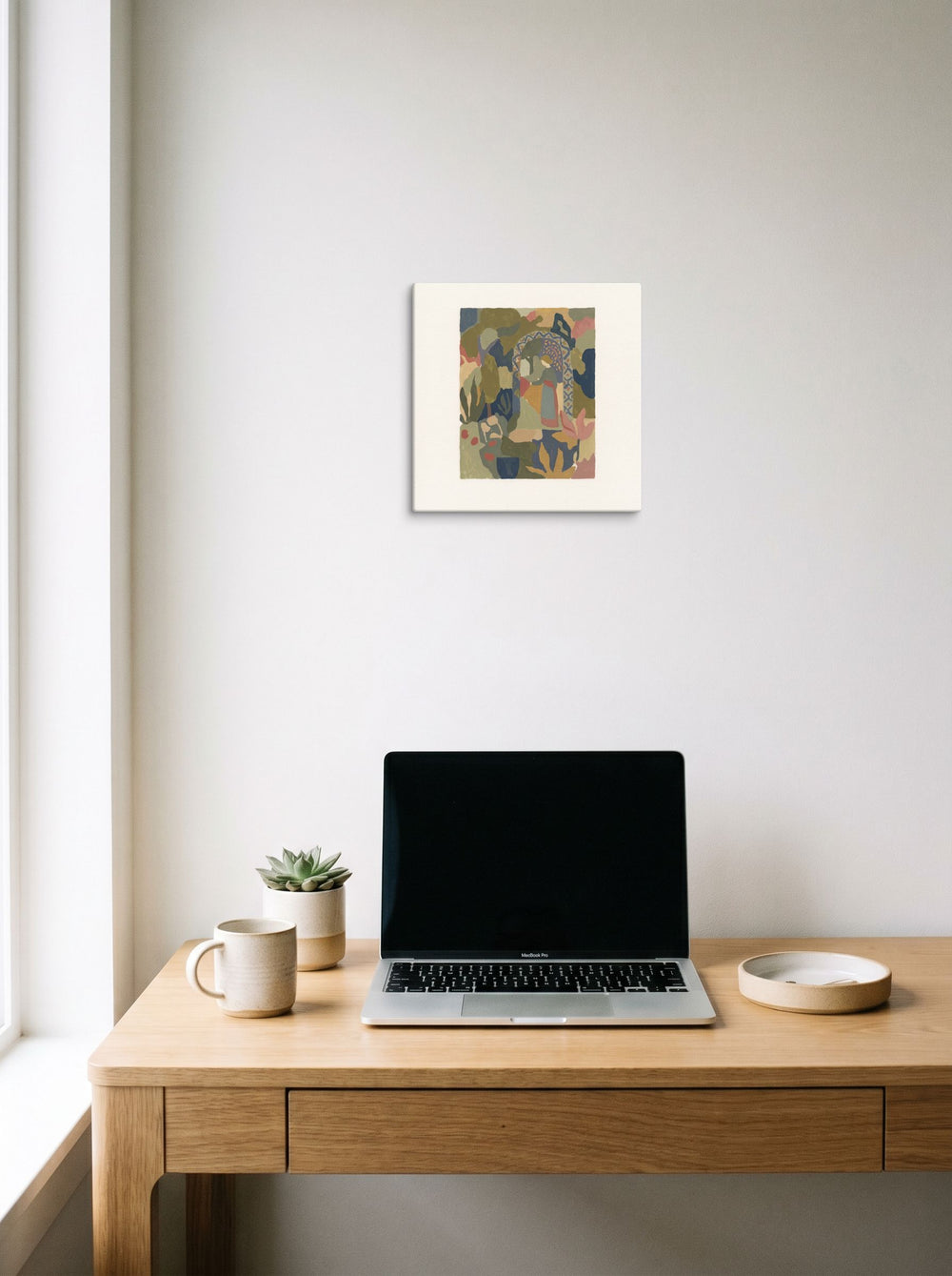 Mockup of 'The Garden Archway' as a 12x12 inch canvas print, hanging above a worktable with a laptop.