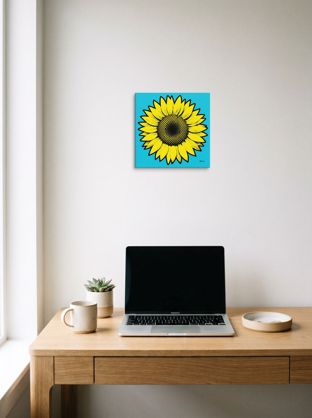 A 12x12 inch canvas Pop art print of 'Cyan Sunflower' hanging above a worktable with a laptop.