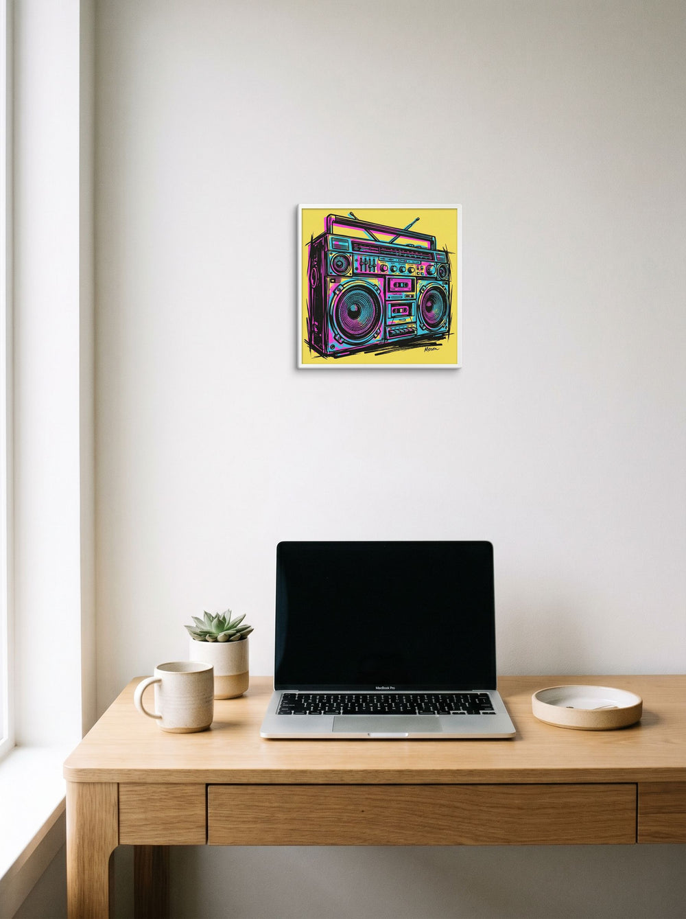 A 12x12 inch canvas Pop art print of 'Neon Boombox' hanging above a worktable with a laptop.