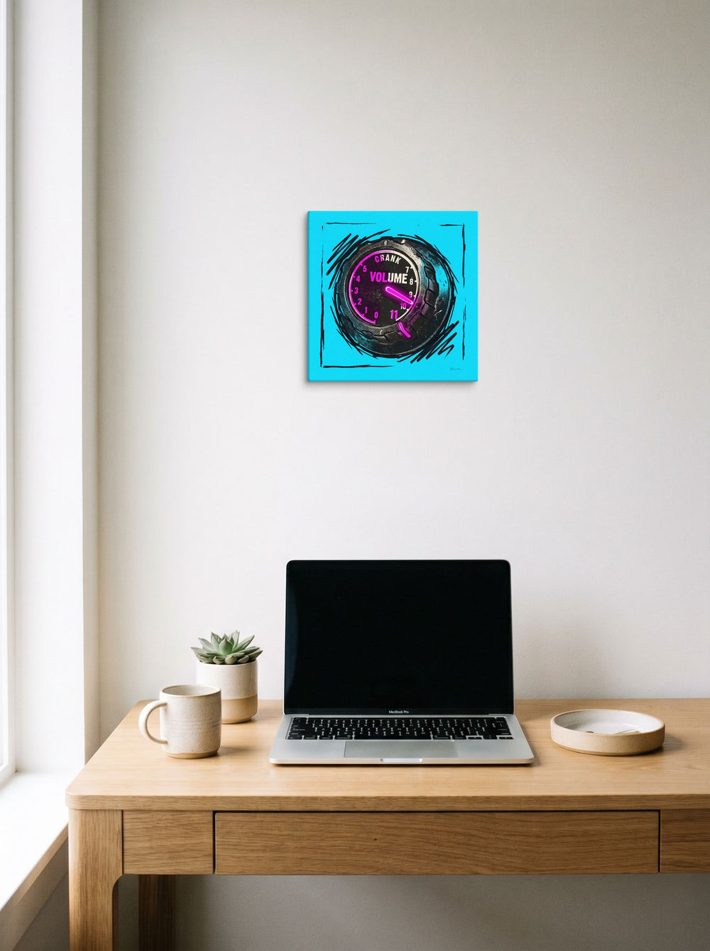 A 12x12 inch canvas Pop art print of 'Crank to Eleven' hanging above a worktable with a laptop.