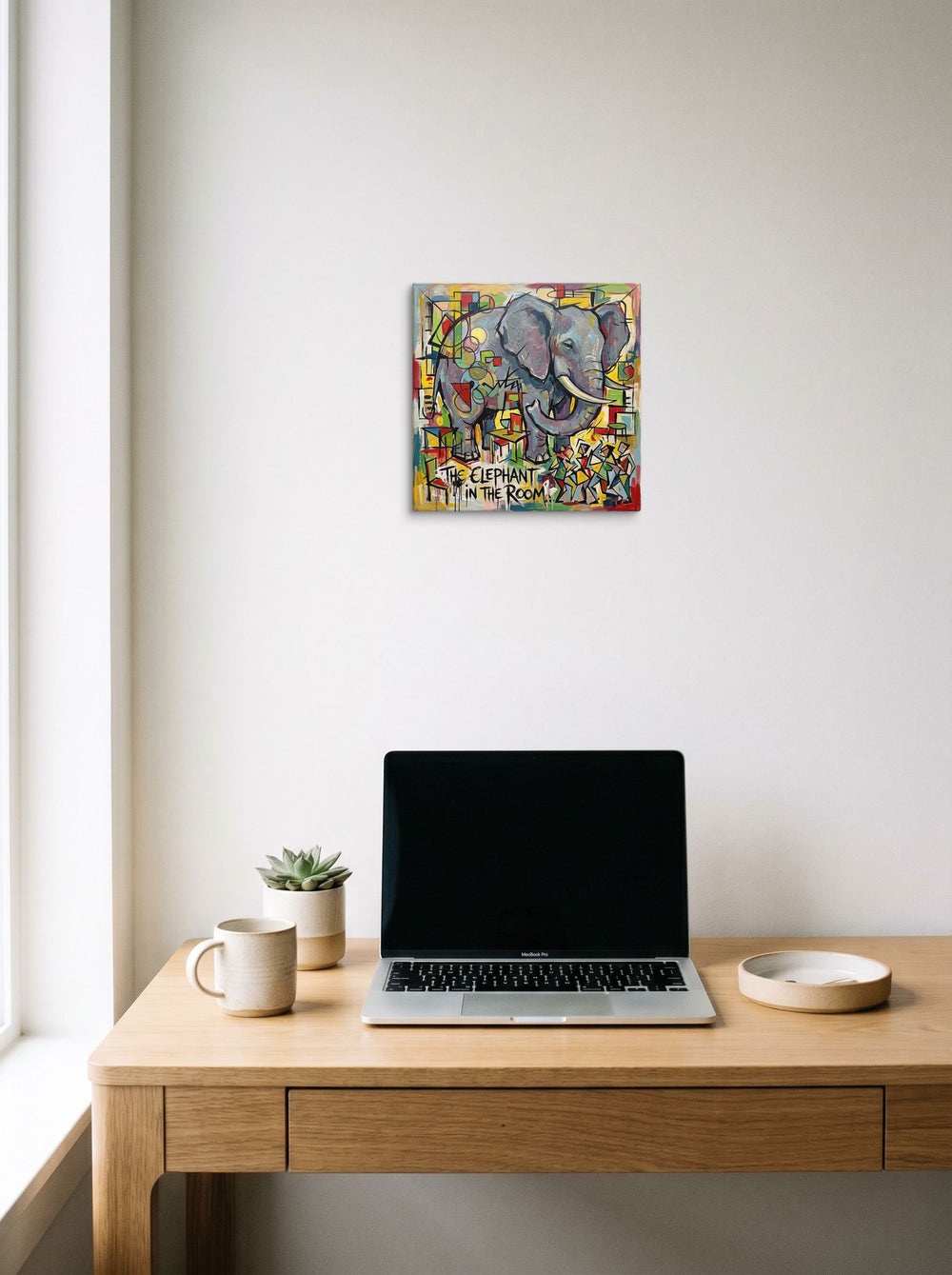 12x12 inch canvas print of 'The Elephant in the Room', styled above a home-office workspace.