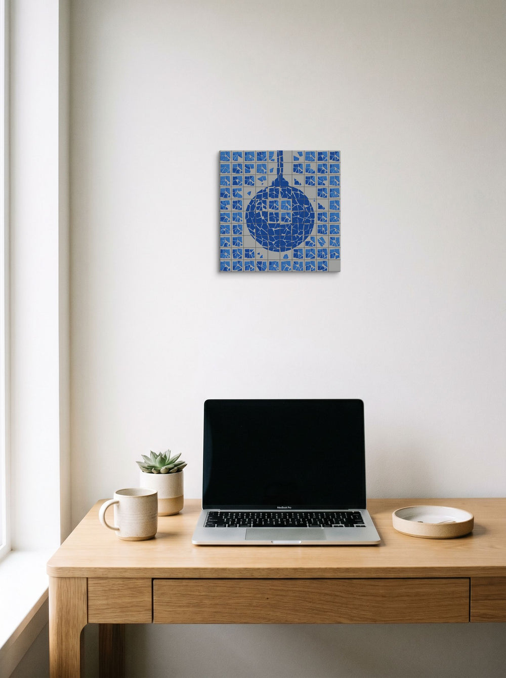 A 12x12 inch canvas Pop art print of 'Shattered Groove' hanging above a worktable with a laptop.