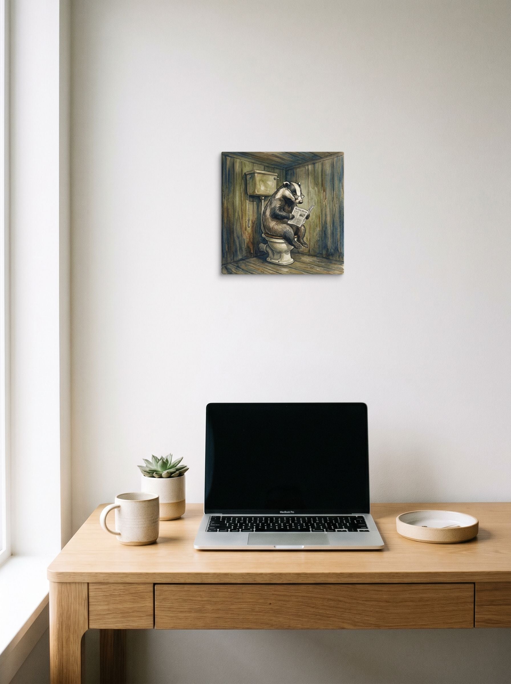 A 12x12 inch canvas Realism print of 'The Daily Burrow' hanging above a worktable with a laptop.