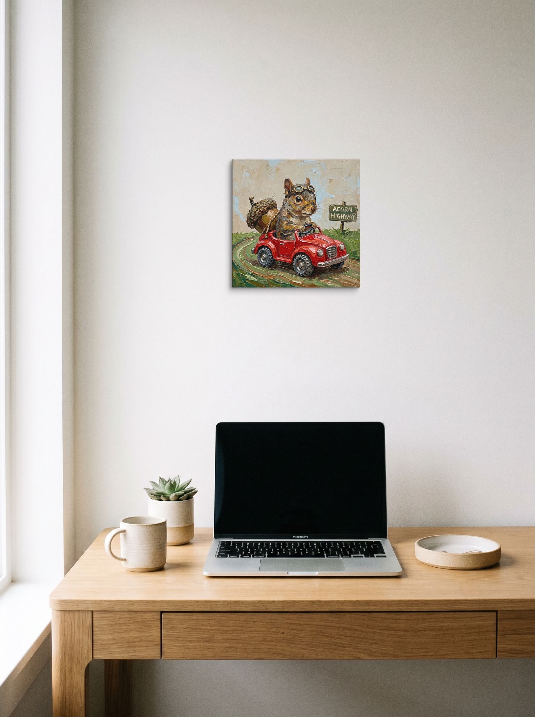 A 12x12 inch canvas Impressionism print of 'Acorn Highway' hanging above a worktable with a laptop.