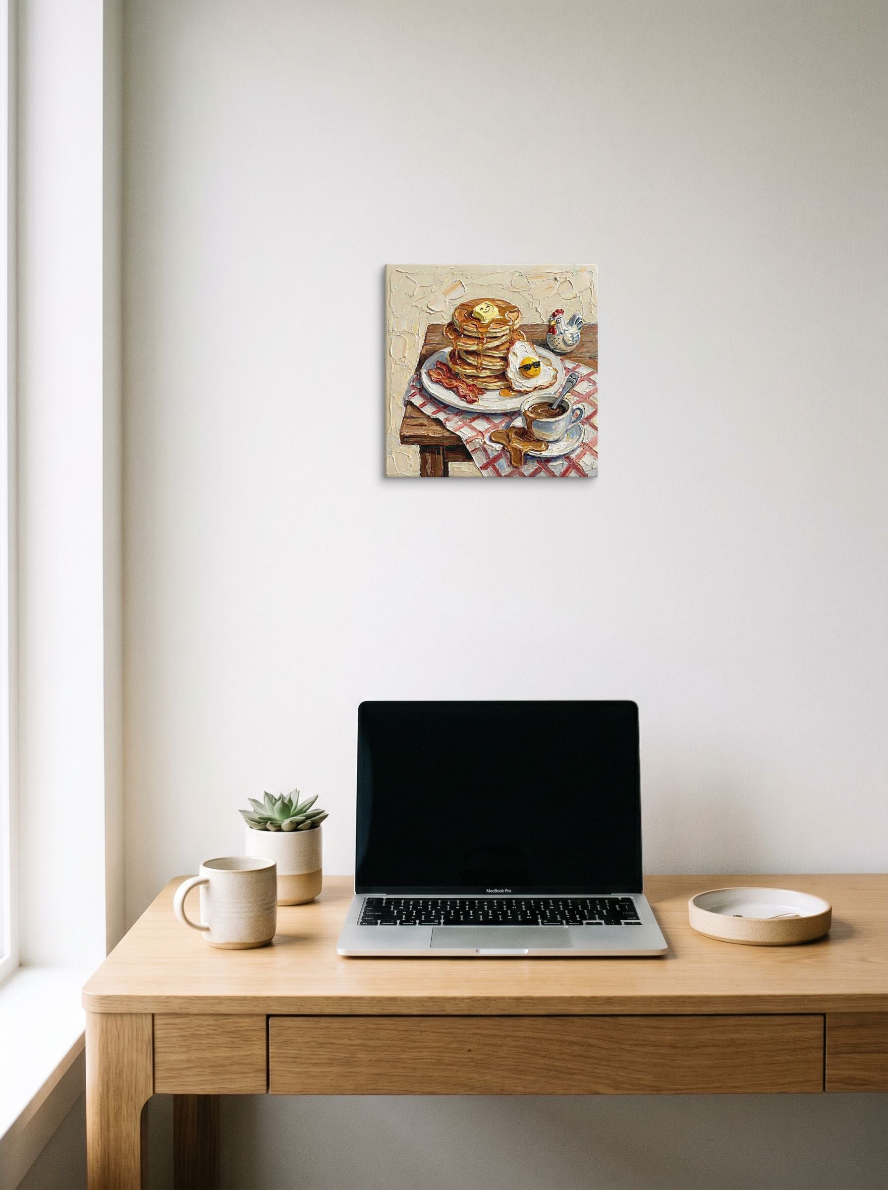 A 12x12 inch canvas Expressionism print of 'A Hearty Morning' hanging above a worktable with a laptop.