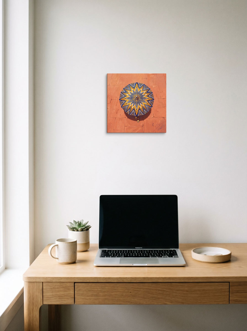 A 12x12 inch canvas Geometric abstract art,Figurative art print of 'The Patterned Parasol' hanging above a worktable with a laptop.