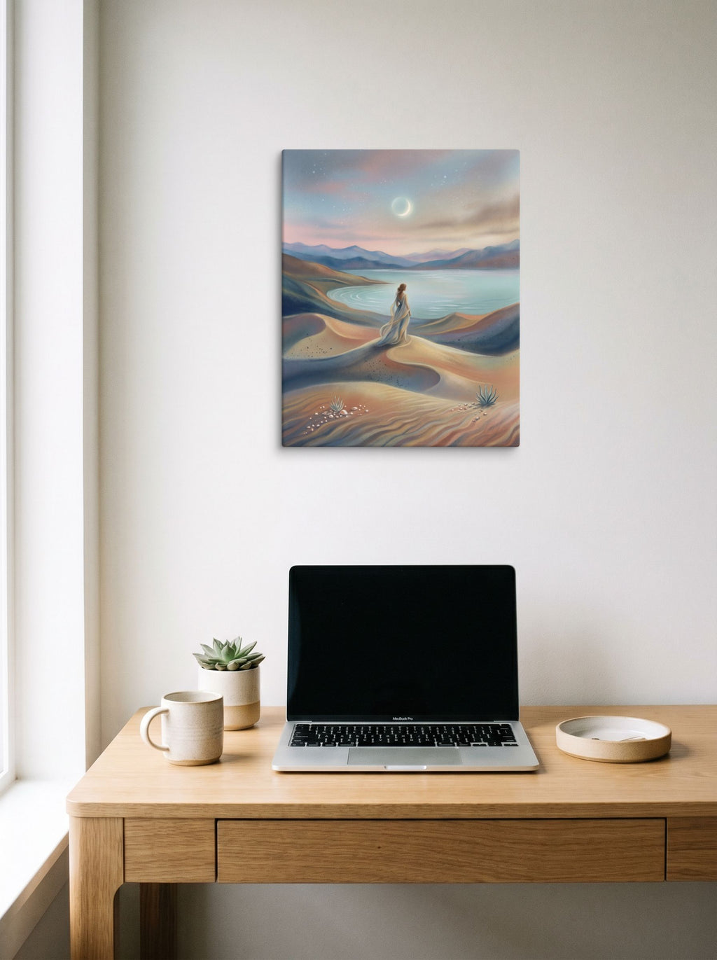 A 16x20 inch canvas Magic realism print of 'Desert Moonrise' hanging above a worktable with a laptop.