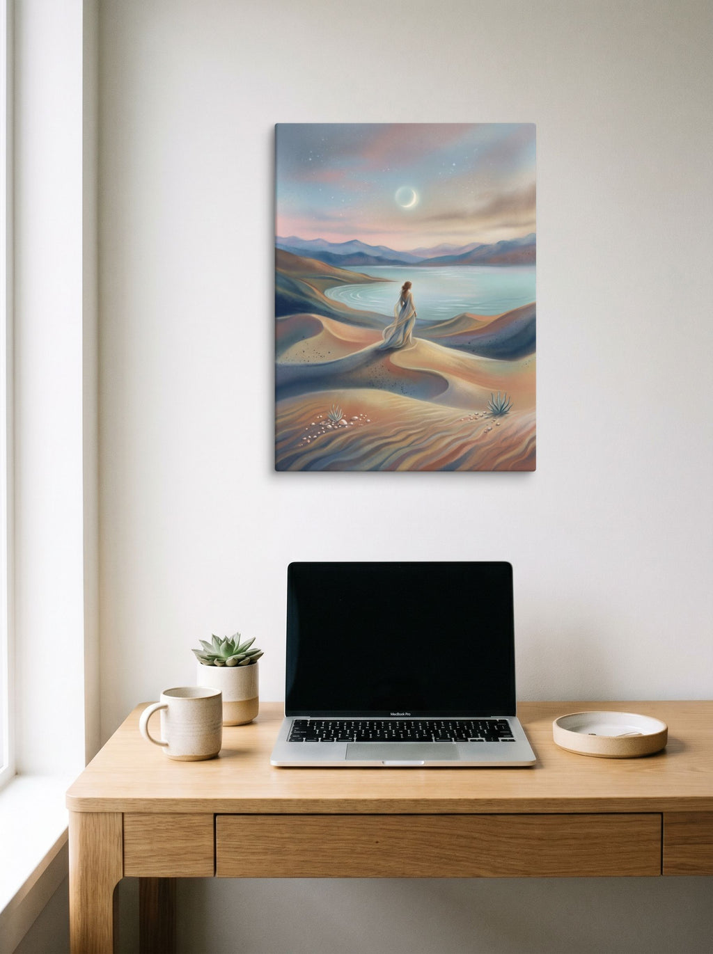 A 18x24 inch canvas Magic realism print of 'Desert Moonrise' hanging above a worktable with a laptop.