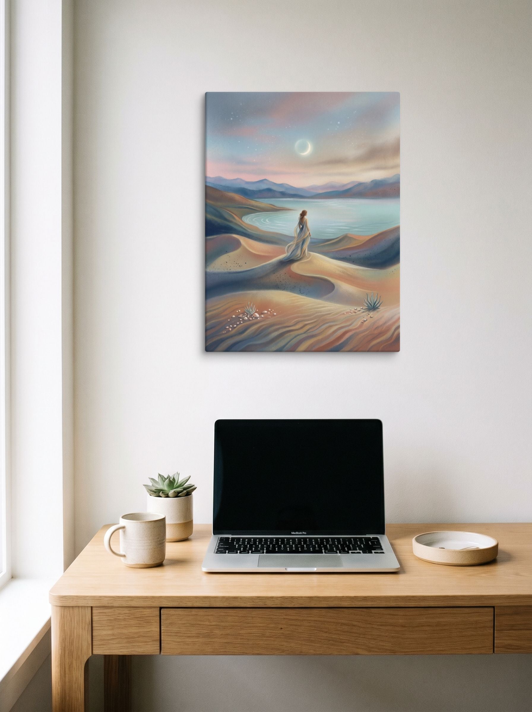A 18x24 inch canvas Magic realism print of 'Desert Moonrise' hanging above a worktable with a laptop.
