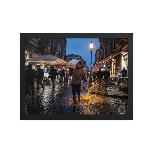 'Market Rain at Dusk' — a Art photography print. Market worker carrying a fish crate splashing through rainy wet cobblestones under a glowing streetlamp at dusk, atmospheric street photography.