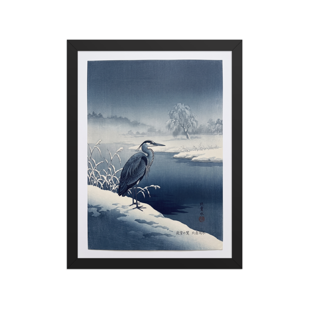 'Winter Heron' — a Shin hanga print. A stately blue heron stands on a snow-covered riverbank along dark winter waters, bringing a serene atmosphere to a calm bedroom.