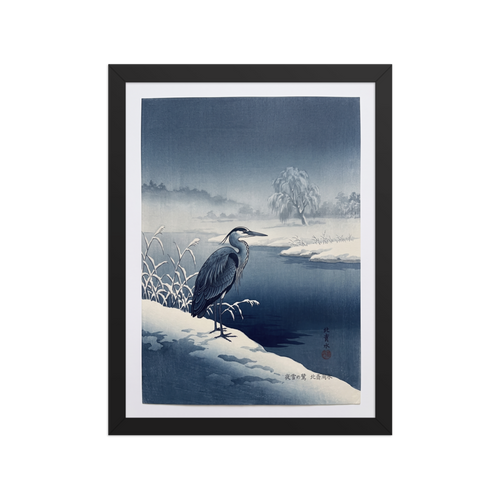 'Winter Heron' — a Shin hanga print. A stately blue heron stands on a snow-covered riverbank along dark winter waters, bringing a serene atmosphere to a calm bedroom.