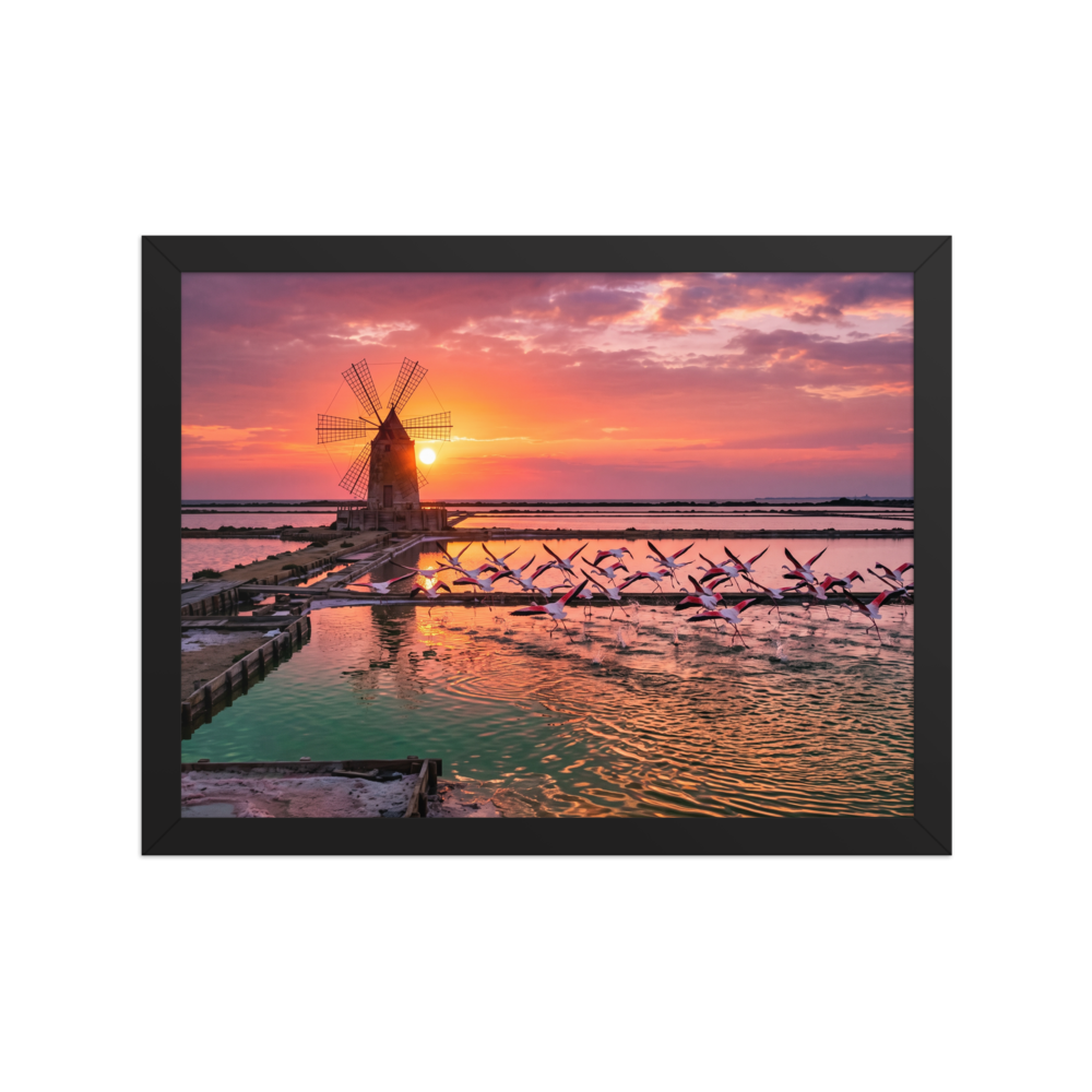 The Art photography print 'Flamingos at Dusk'. A breathtaking photograph of pink flamingos flying across tranquil salt pans at sunset near a traditional windmill, perfect for a peaceful bedroom or living room.