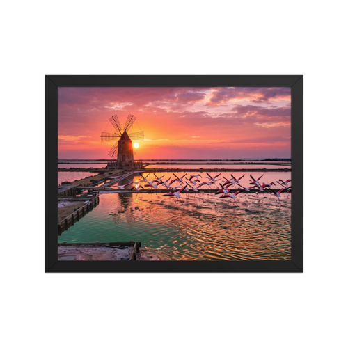 The Art photography print 'Flamingos at Dusk'. A breathtaking photograph of pink flamingos flying across tranquil salt pans at sunset near a traditional windmill, perfect for a peaceful bedroom or living room.