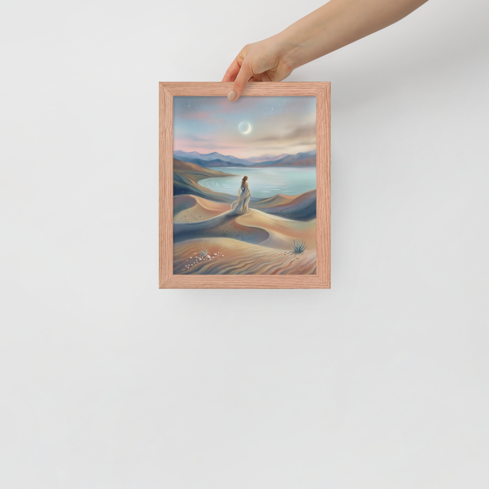'Desert Moonrise' — a Magic realism print. A woman in a flowing dress standing on rolling sand dunes looking over a turquoise bay toward mountains under a twilight sky with a crescent moon.