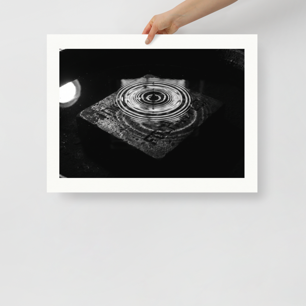 'Concentric Resonance' — a Art photography print. A dramatic black and white photograph capturing concentric water ripples above a textured stone, well suited for a modern office or living room.