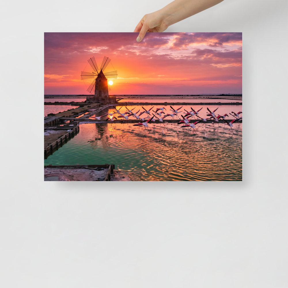 A breathtaking photograph of pink flamingos flying across tranquil salt pans at sunset near a traditional windmill, perfect for a peaceful bedroom or living room. A Art photography print in coral and orange red, 'Flamingos at Dusk'.