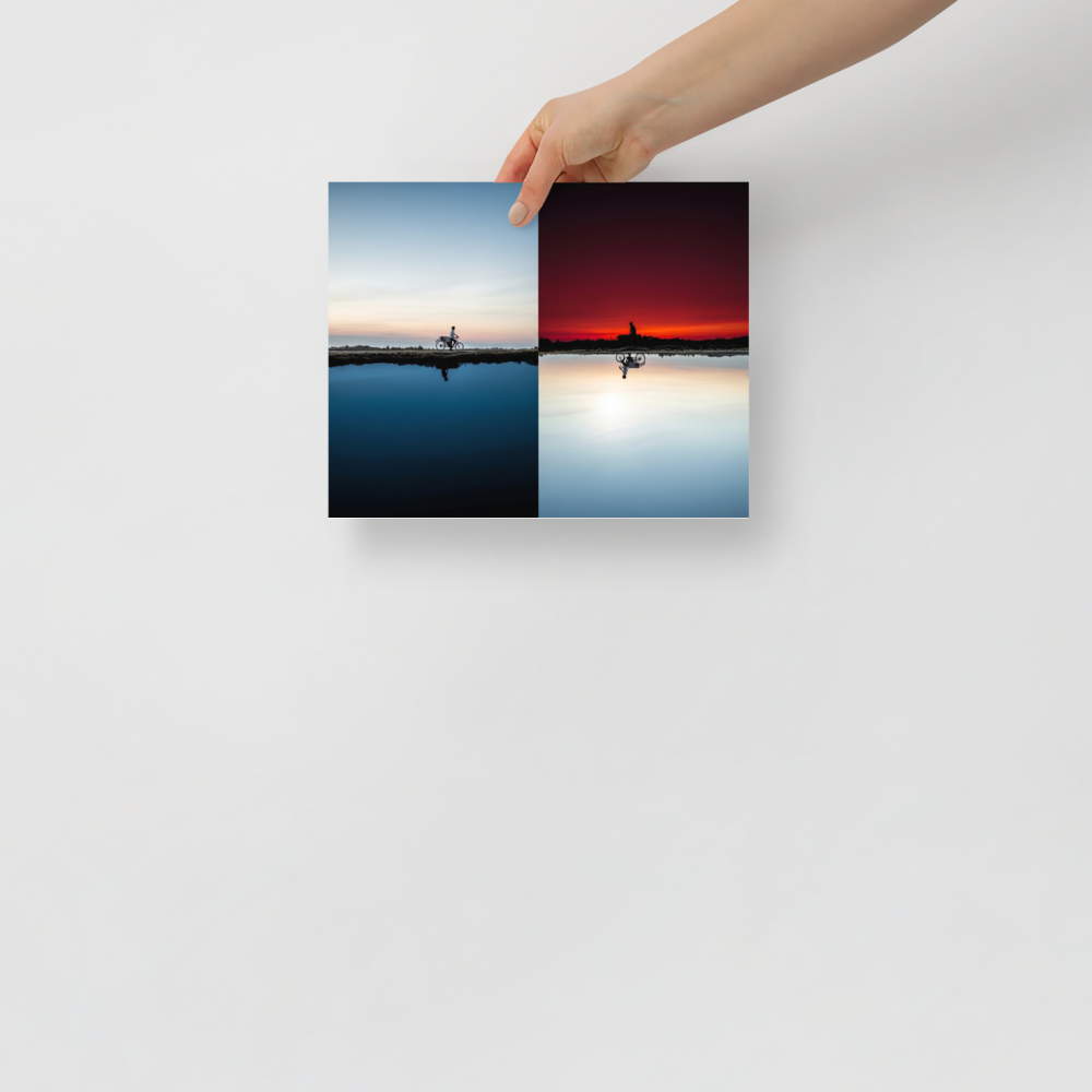 'Two Worlds Riding' — a Surrealism print. A split horizon image showing a cyclist riding in twilight blue on top and an inverted red sunset on the bottom.