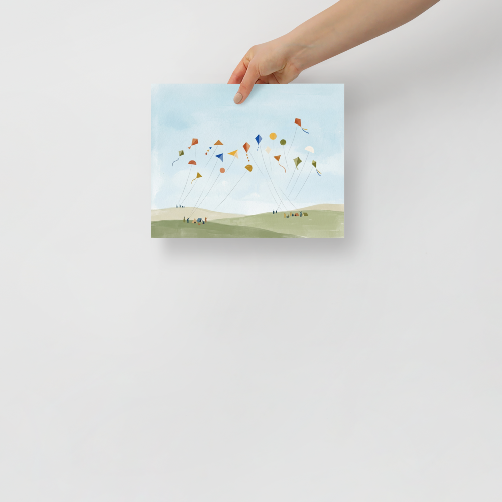 'Kite Festival' — a Minimalism,Naive art print. A playful minimalist painting showing numerous colorful geometric kites flying high in a light blue sky, held by tiny figures on soft green and beige hills. Perfect for a nursery or playroom.