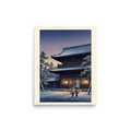'Snowfall at Dusk' — a Shin hanga print. Two figures walk through falling snow toward an illuminated Japanese temple gate at dusk, creating a peaceful scene ideal for a living room.