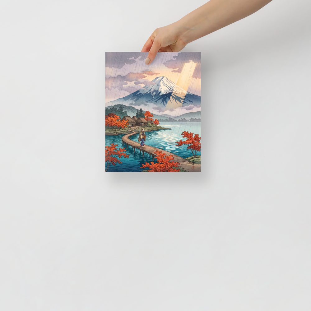 'Sunshower Over Fuji' — a Shin hanga print. A lone traveler walks across a wooden bridge on a tranquil lake toward Mount Fuji as sun rays pierce through light rainfall, ideal for an office.