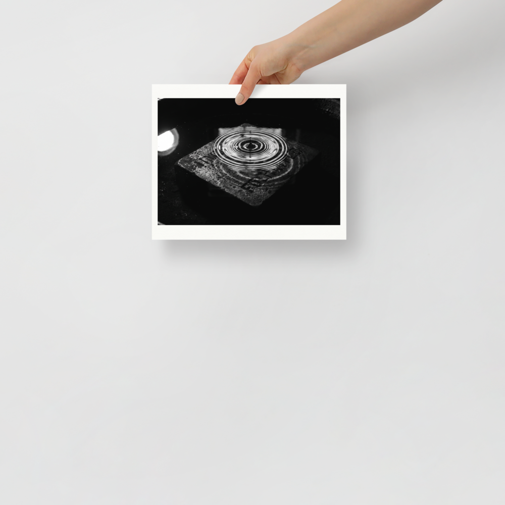'Concentric Resonance' — a Art photography print. A dramatic black and white photograph capturing concentric water ripples above a textured stone, well suited for a modern office or living room.