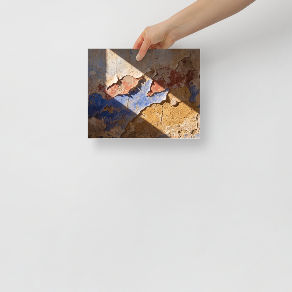 'Palimpsest in Sunlight' — a Art photography print. A photographic study of peeling plaster wall showing layers of blue, red, and ochre paint under bright diagonal sunlight, suitable for a rustic or modern living room.