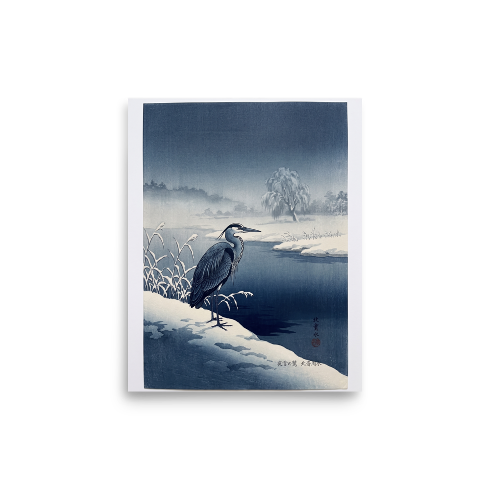'Winter Heron' — a Shin hanga print. A stately blue heron stands on a snow-covered riverbank along dark winter waters, bringing a serene atmosphere to a calm bedroom.