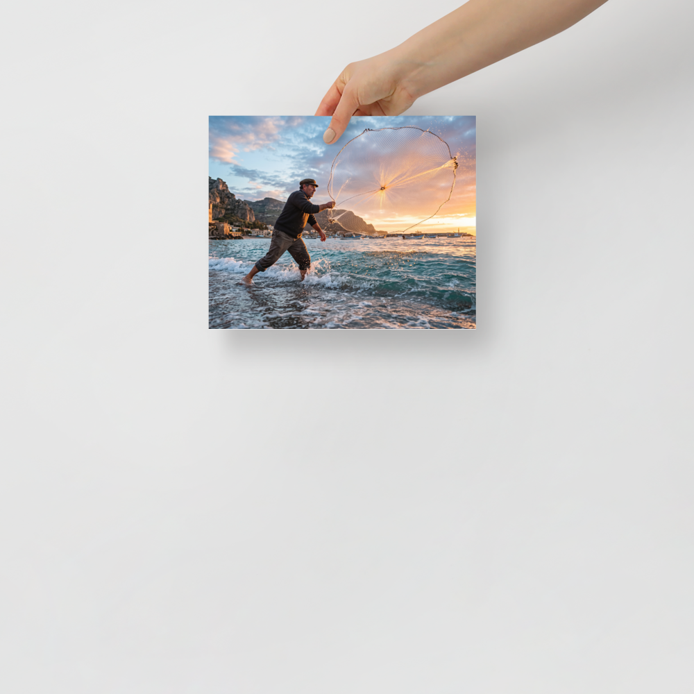 'Casting the Dawn' — a Art photography print. A dynamic photograph of a fisherman casting a circular net that catches golden sunrise light over the sea, ideal for a living room or study.