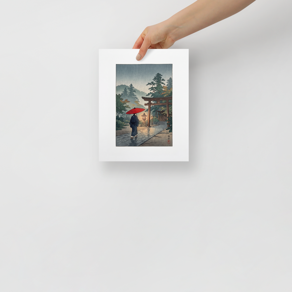 'Sanctuary in the Rain', a Shin hanga wall art print. A person holding a red umbrella walks along a rain-slicked stone path toward an illuminated shrine gate in misty woods, ideal for a calm living room.