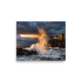 'Citadel of the Waves' by Meron. A dramatic photograph of a massive golden wave crashing against rocky cliffs below an ancient coastal castle under storm clouds, perfect for a living room or study. A Art photography wall art print.