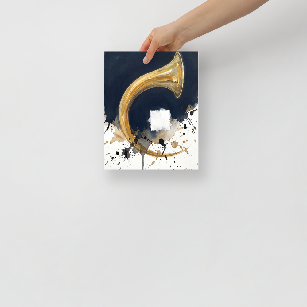 'Crescendo in Gold', a Abstract expressionism wall art print. A metallic gold brass horn arc with dark blue ink wash and black ink splatters on white paper in a living room wall art display.