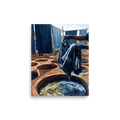 Wall art print 'The Indigo Dyer' in a Realism style. Artisan hands lifting patterned blue cloth from a sunlit clay indigo dye pit, suitable for an artist studio.