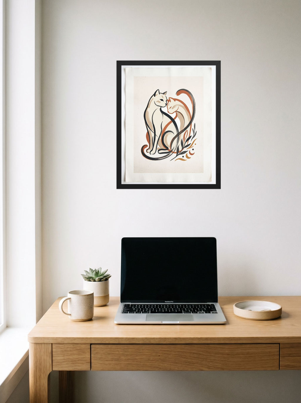 A 16x20 inch black framed Minimalism,Abstract art print of 'Feline Affection' hanging above a worktable with a laptop.