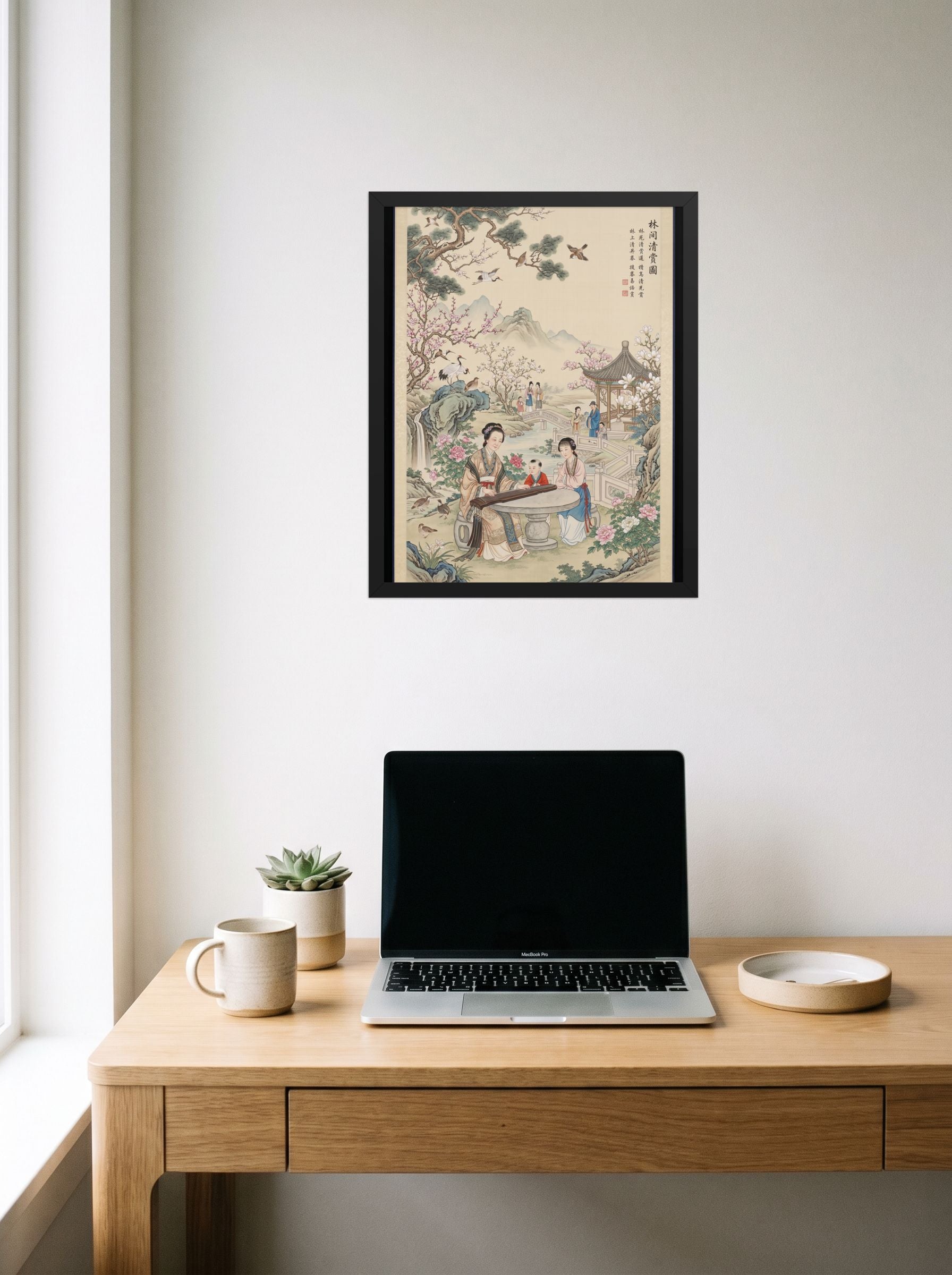 A 16x20 inch black framed Fine Art print of 'Melody in the Spring Garden' hanging above a worktable with a laptop.