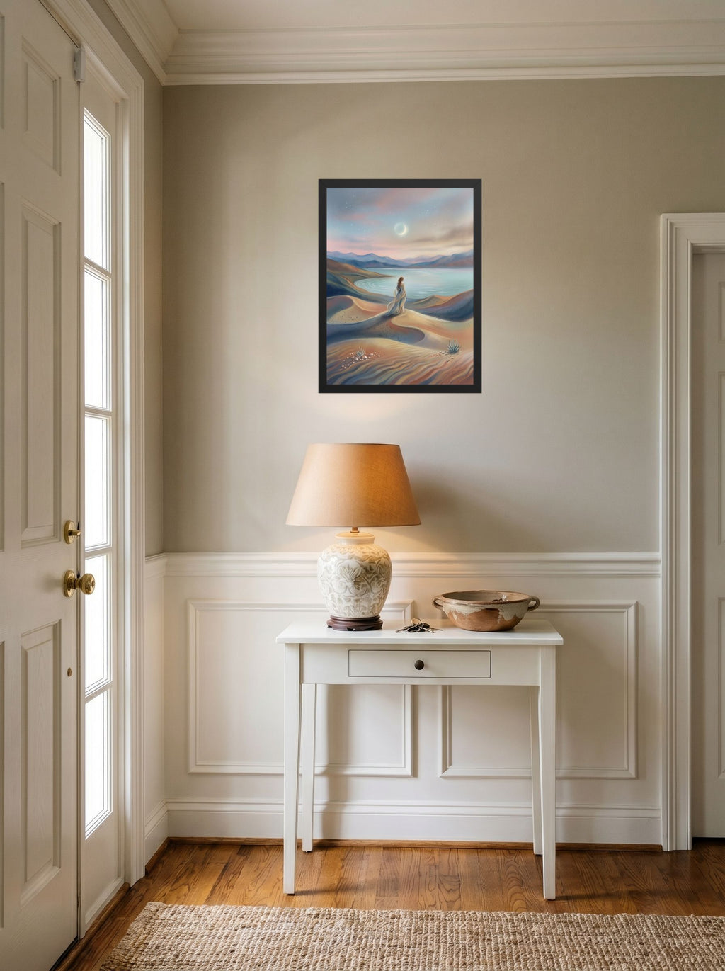 A 18x24 inch black framed Magic realism print of 'Desert Moonrise' hanging in an entryway near a console.