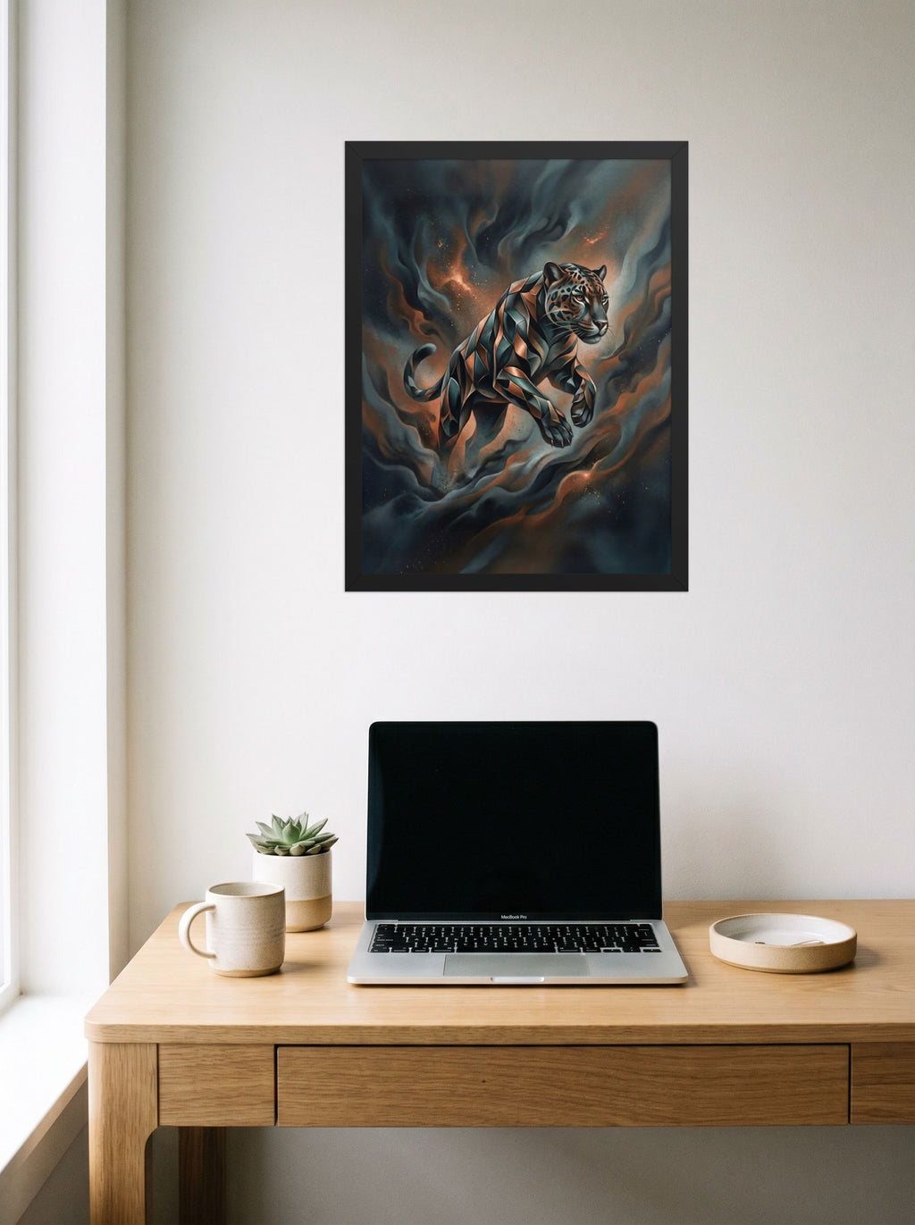 A 18x24 inch black framed Digital art print of 'Phantom Leap' hanging above a worktable with a laptop.