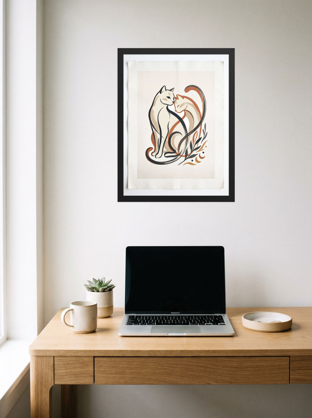 A 18x24 inch black framed Minimalism,Abstract art print of 'Feline Affection' hanging above a worktable with a laptop.