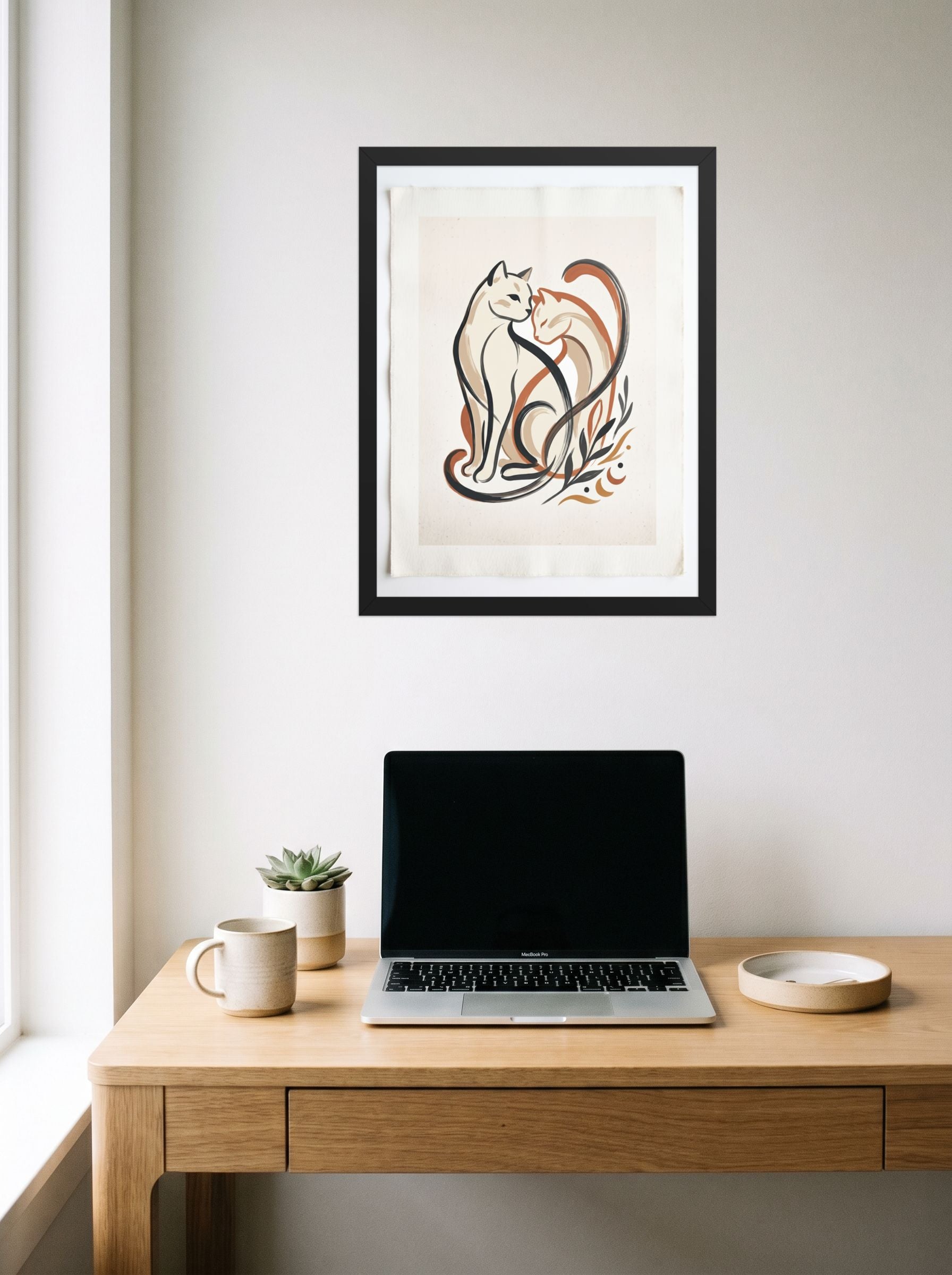 A 18x24 inch black framed Minimalism,Abstract art print of 'Feline Affection' hanging above a worktable with a laptop.