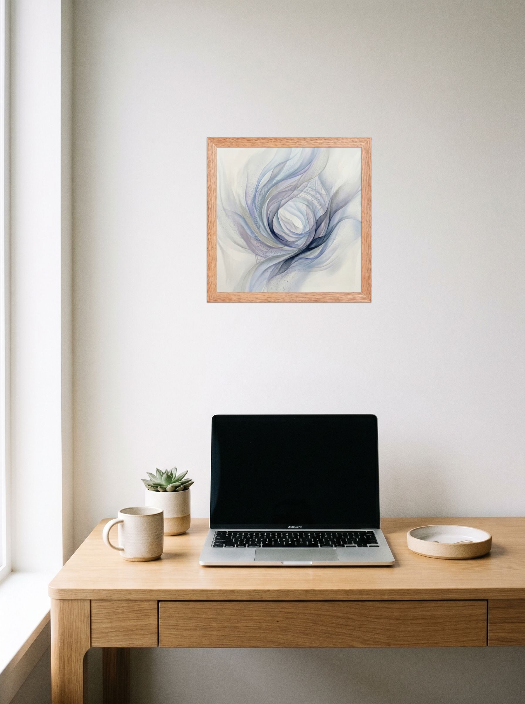 A 12x12 inch redoak framed Abstract art print of 'Ethereal Whispers in the Vortex' hanging above a worktable with a laptop.