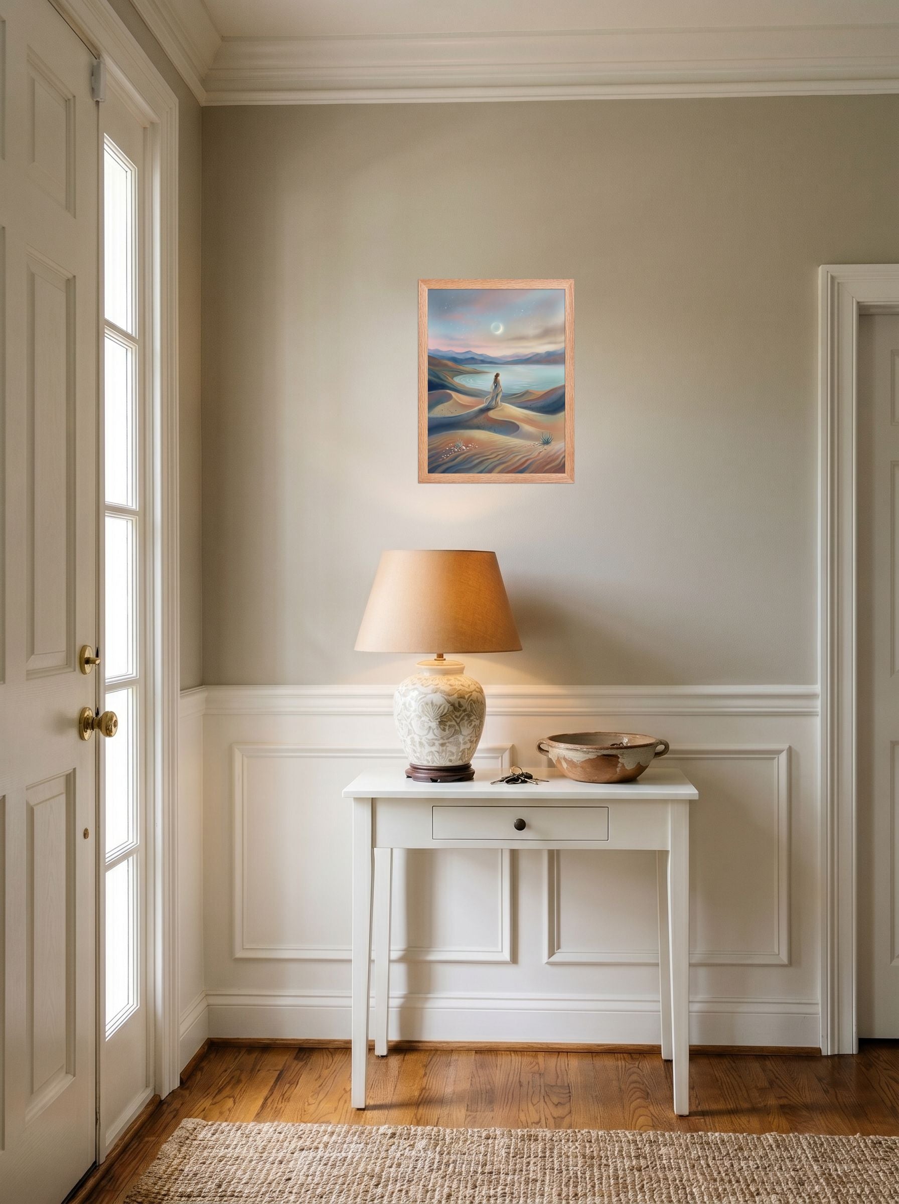 A 12x16 inch redoak framed Magic realism print of 'Desert Moonrise' hanging in an entryway near a console.