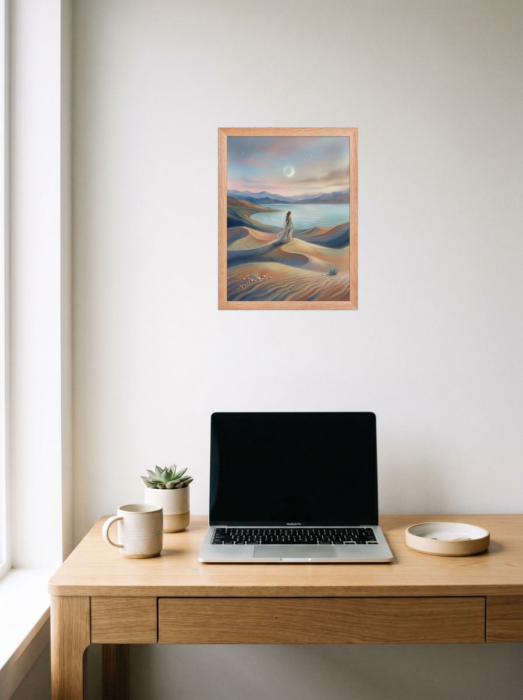 A 12x16 inch redoak framed Magic realism print of 'Desert Moonrise' hanging above a worktable with a laptop.