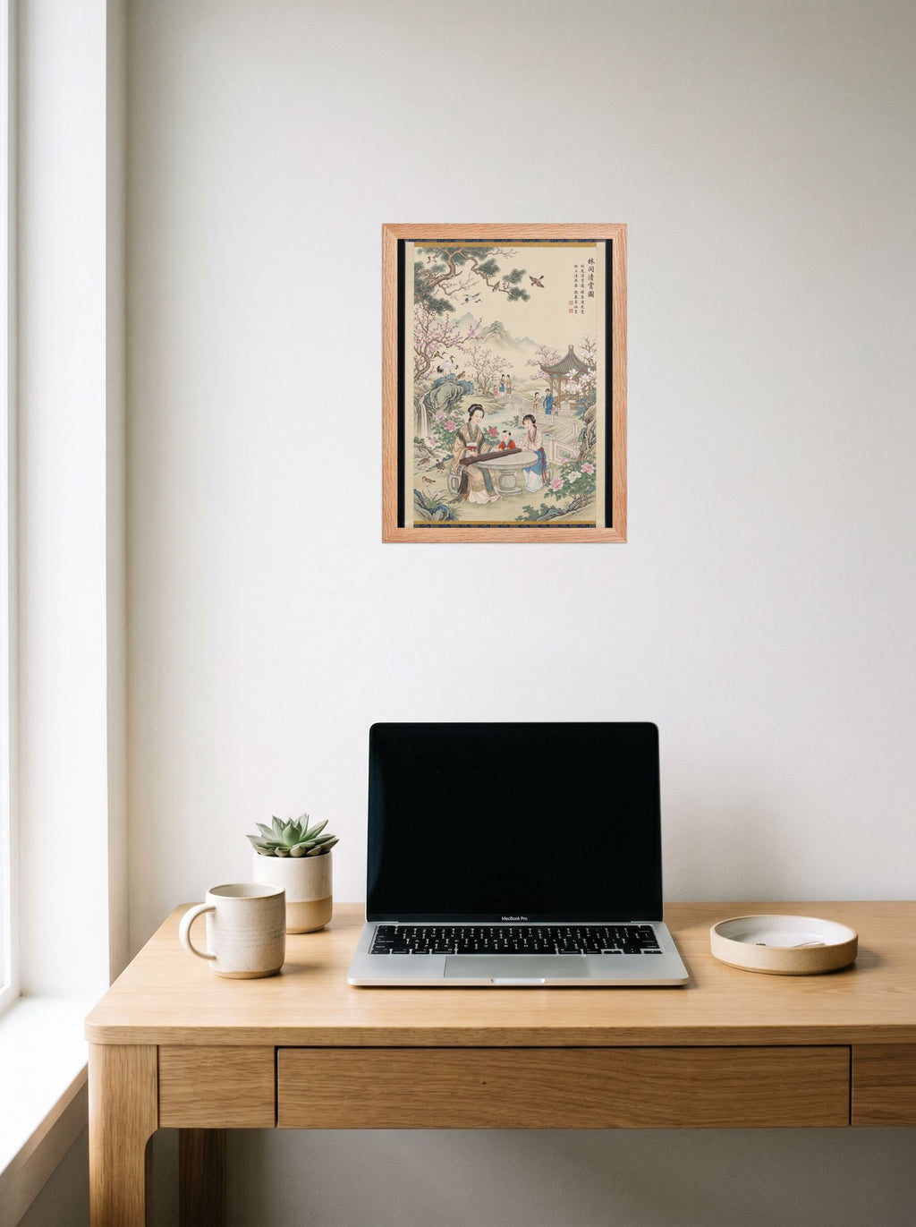 A 12x16 inch redoak framed Fine Art print of 'Melody in the Spring Garden' hanging above a worktable with a laptop.