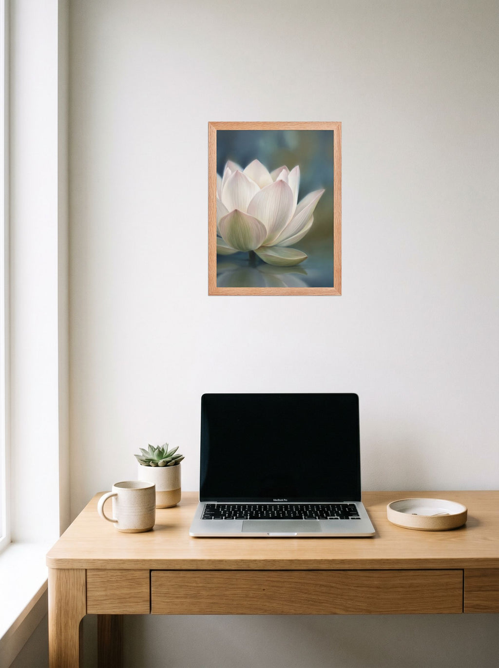 A 12x16 inch redoak framed Realism print of 'Serene Lotus Reflection' hanging above a worktable with a laptop.