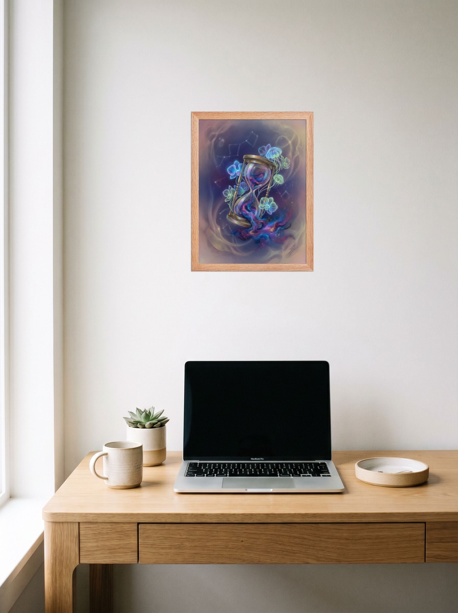 A 12x16 inch redoak framed Magic realism print of 'Sands of the Nebula' hanging above a worktable with a laptop.