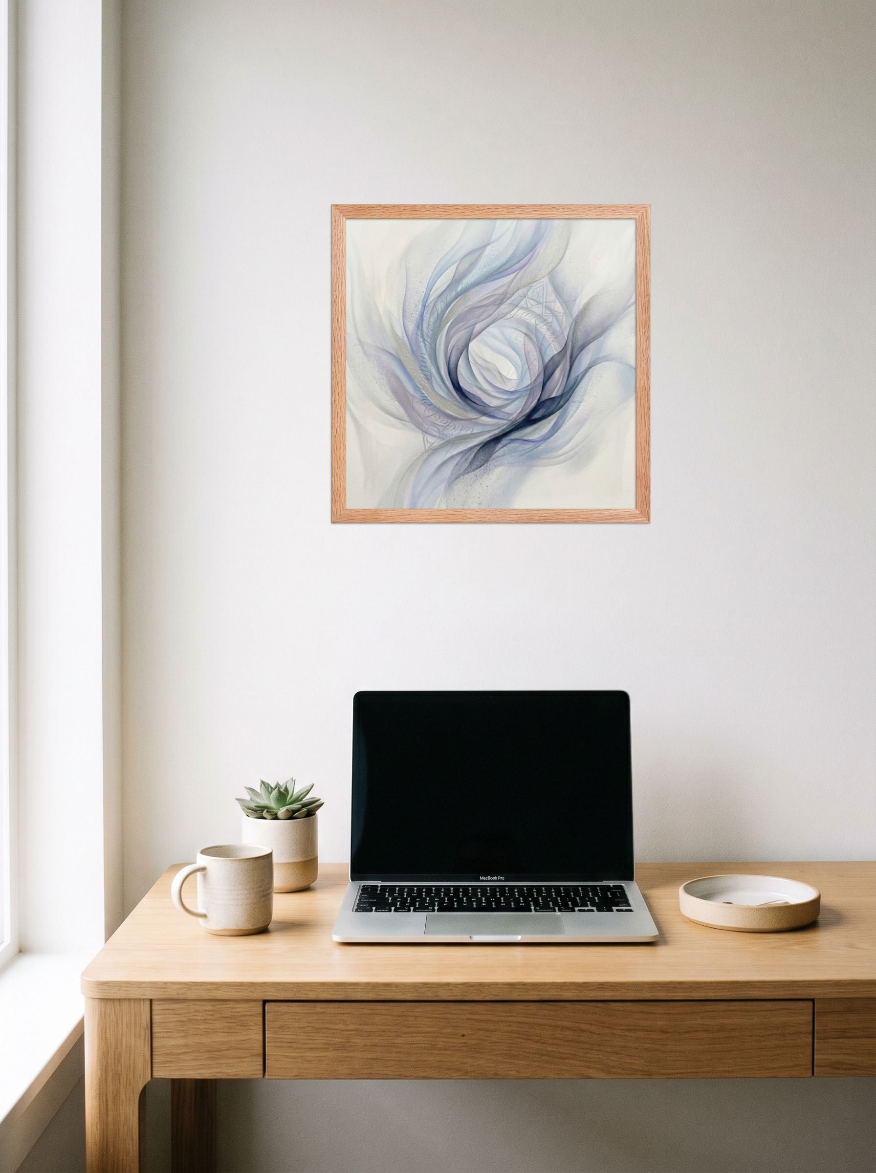 A 16x16 inch redoak framed Abstract art print of 'Ethereal Whispers in the Vortex' hanging above a worktable with a laptop.