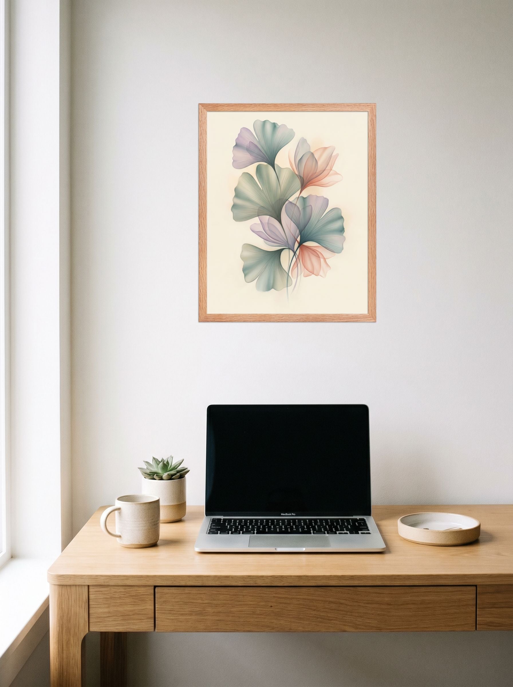 A 16x20 inch redoak framed Abstract art print of 'Ethereal Ginkgo Whispers' hanging above a worktable with a laptop.