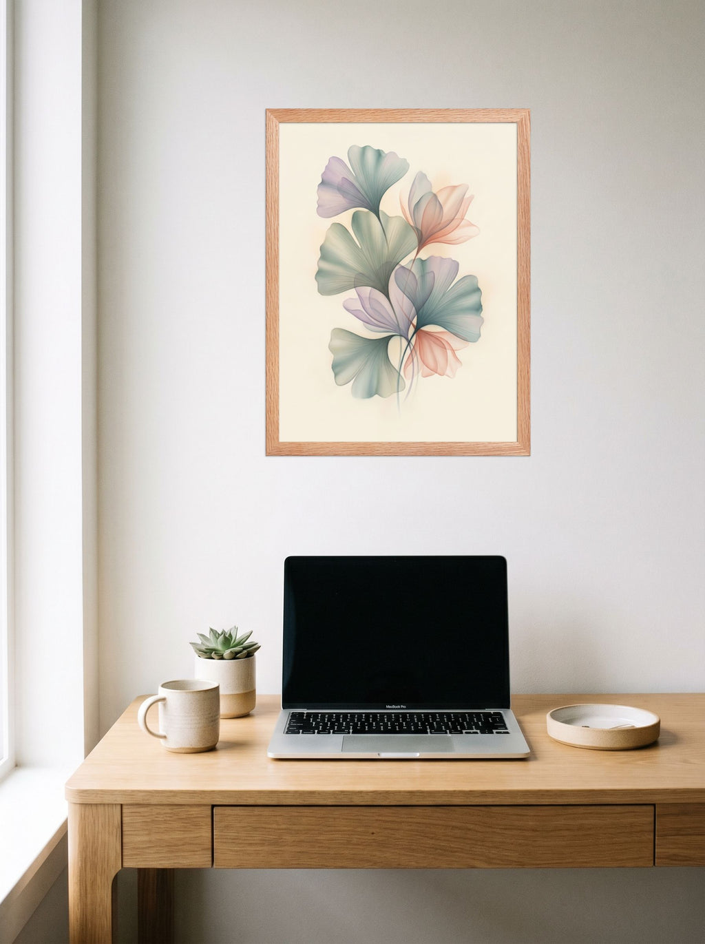 A 18x24 inch redoak framed Abstract art print of 'Ethereal Ginkgo Whispers' hanging above a worktable with a laptop.