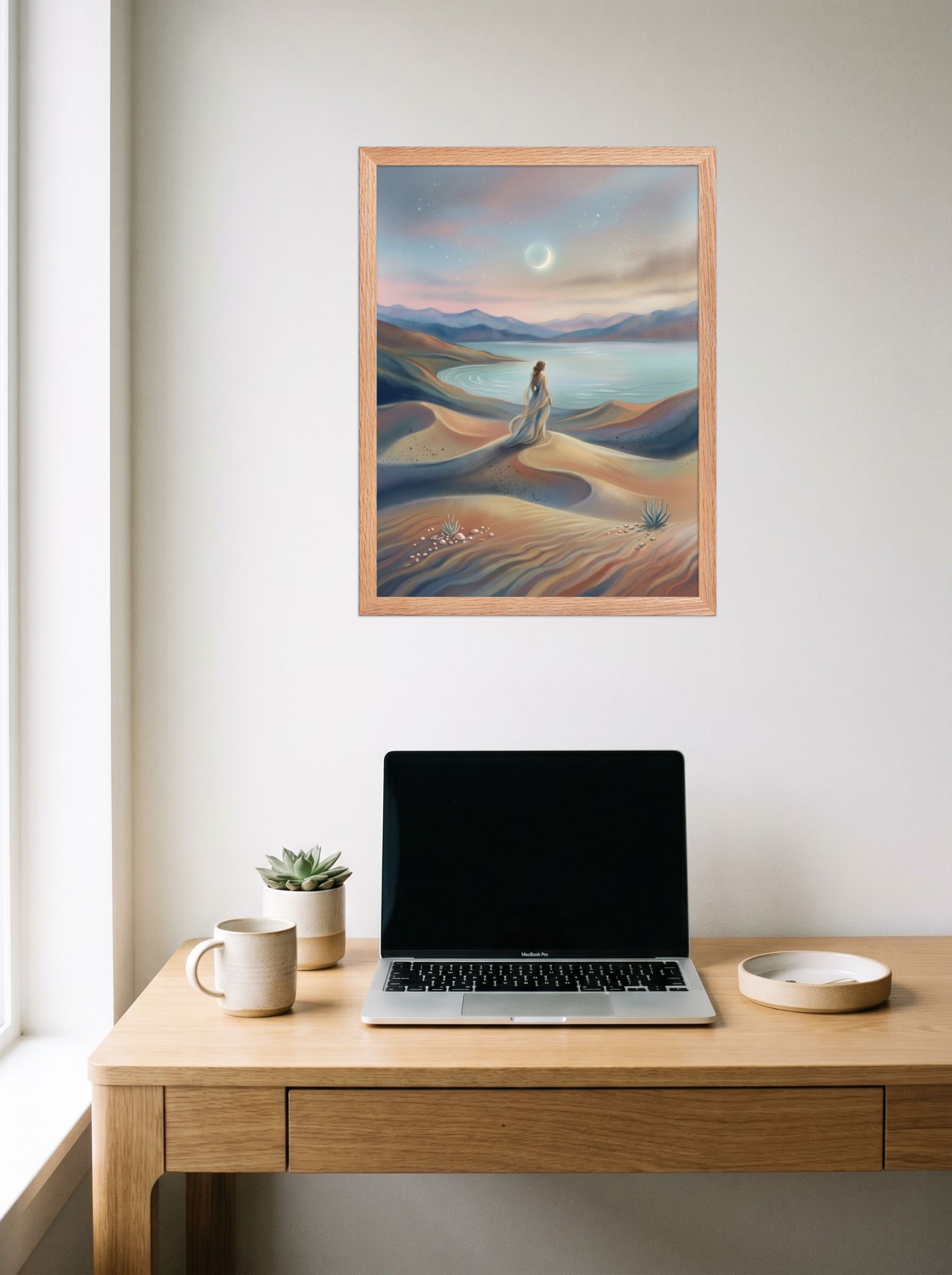 A 18x24 inch redoak framed Magic realism print of 'Desert Moonrise' hanging above a worktable with a laptop.